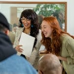 A diverse group of colleagues laughing and enjoying a meeting indoors, showcasing teamwork and camaraderie.